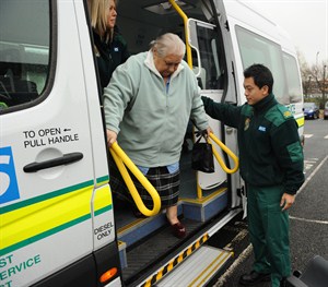 Patient being helped by an ambulance driver from a patient transport vehicle